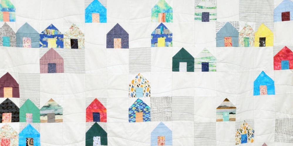 A quilt with a pattern of different colored houses.