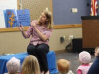 Two librarians give a presentation with puppets to an enthralled audience of children and adults