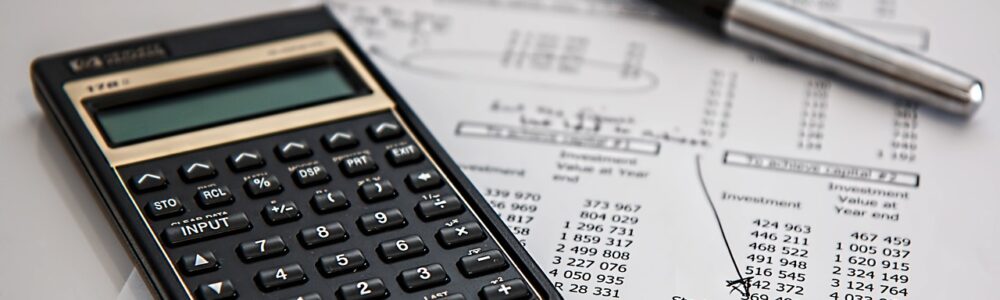 A stock image of a printed budget paper with notes, and a black simple calculator.