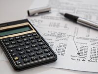 A stock image of a printed budget paper with notes, and a black simple calculator.