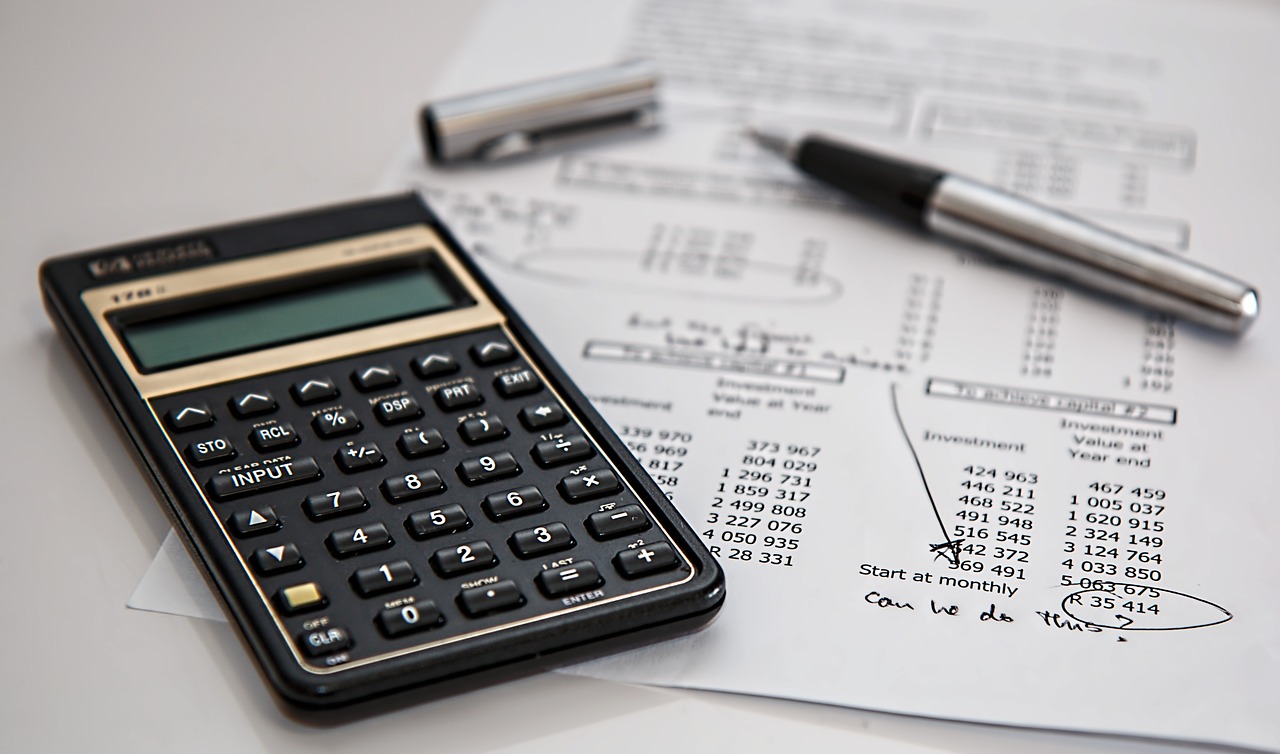 A stock image of a printed budget paper with notes, and a black simple calculator.